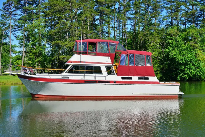 Slide: The Image of 1984 Wellcraft 44 Californian CMY yacht on a serene lake with lush green trees. - 3