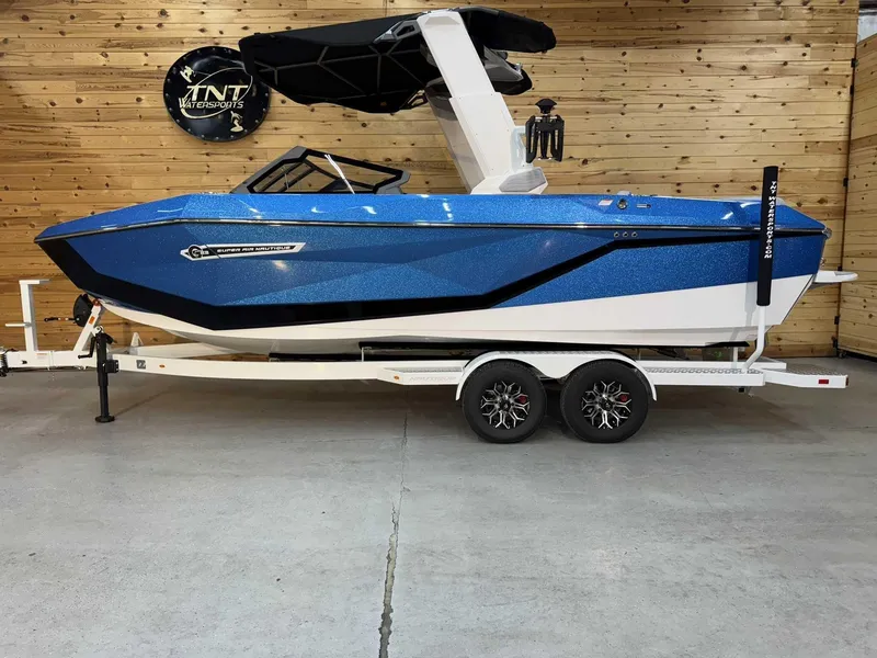 Slide: The Image of 2025 Nautique G23 boat in blue on a trailer, displayed indoors. - 1