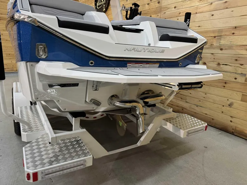 Slide: The Image of 2025 Nautique G23 boat rear view with blue and white design, displayed indoors. - 3