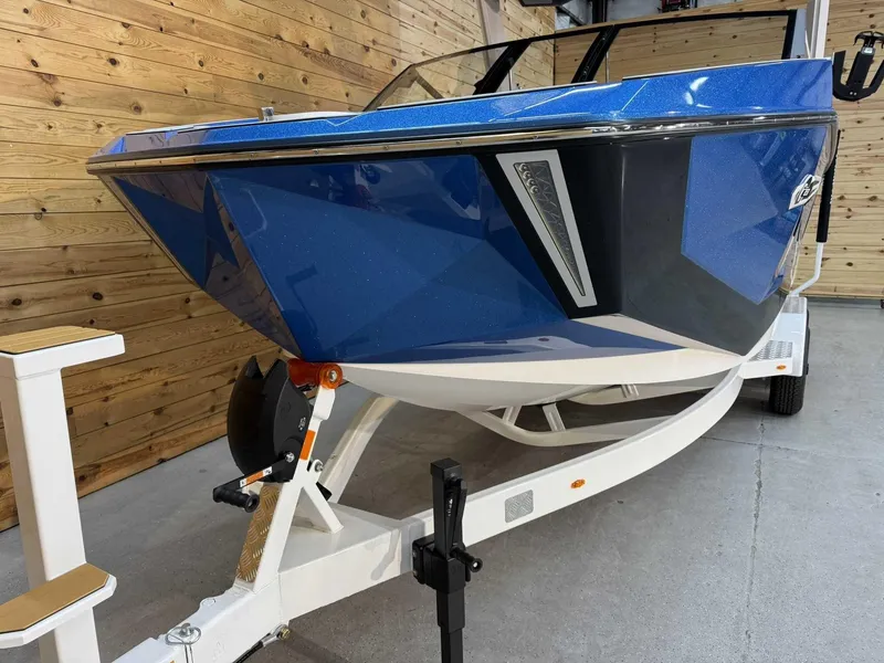 Slide: The Image of 2025 Nautique G23 boat in blue on a trailer, displayed indoors. - 6