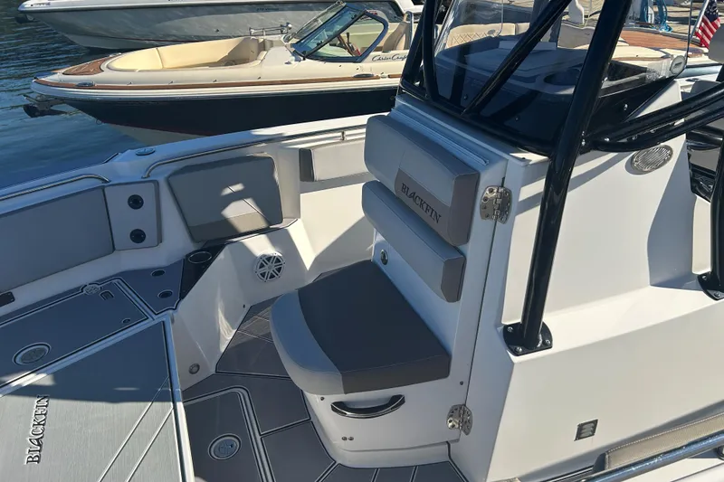 Slide: The Image of 2018 Blackfin 242 CC boat interior with seating and console, docked near other boats. - 10