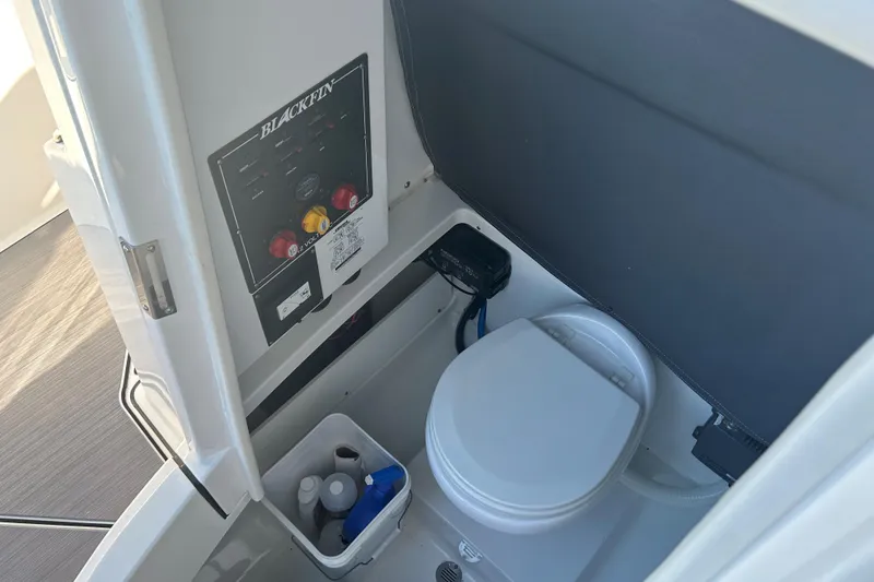 Slide: The Image of Interior of 2018 Blackfin 242 CC boat featuring a compact marine toilet setup. - 11