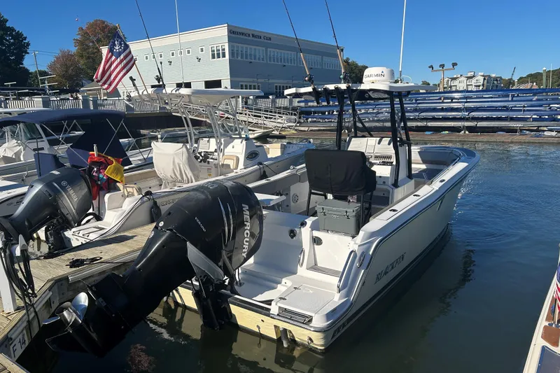 Slide: The Image of 2018 Blackfin 242 CC boat docked at marina with outboard motor. - 2