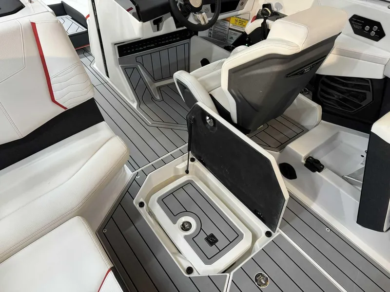 Slide: The Image of 2025 Nautique G23 interior with open storage compartment, white and gray seating, and modern design. - 10