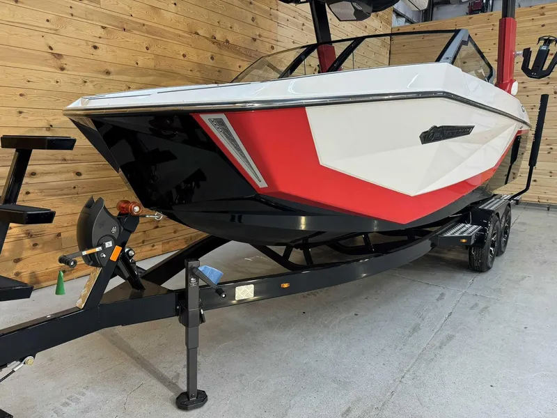 Slide: The Image of 2025 Nautique G23 boat with red and white design on a trailer in a wooden garage. - 4