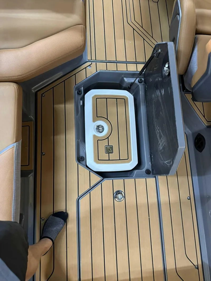 Slide: The Image of 2025 Nautique G23 boat interior with open storage compartment and teak flooring. - 12