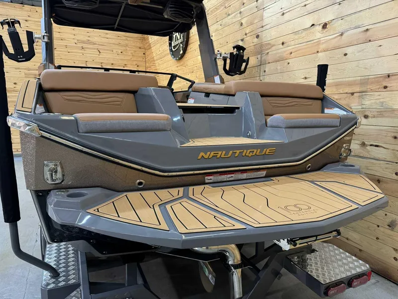 Slide: The Image of 2025 Nautique G23 boat with teak deck, displayed indoors against wooden walls. - 3