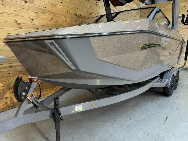 Slide: The Image of 2025 Nautique G23 boat on trailer, parked indoors, wooden wall background. - 6