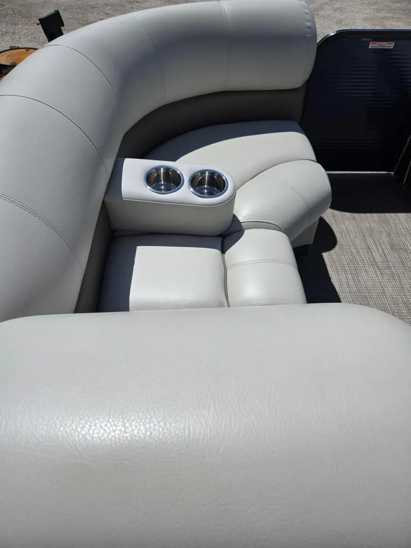 Slide: The Image of 2019 Manitou Oasis VP Tri Toon boat interior with plush seating and cup holders. - 16