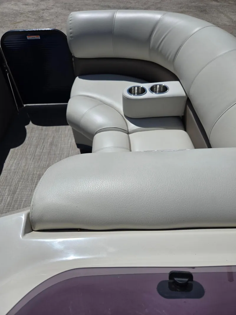 Slide: The Image of 2019 Manitou Oasis VP Tri Toon boat interior with plush seating and cup holders. - 17