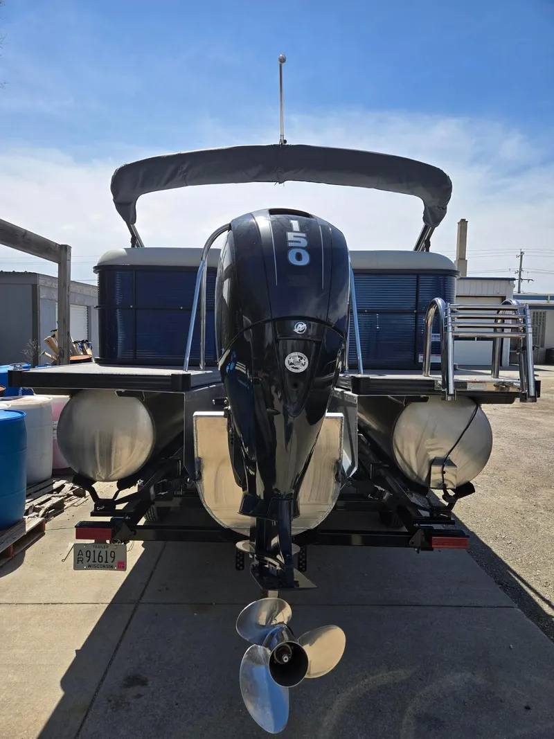 Slide: The Image of 2019 Manitou Oasis VP Tri Toon boat with powerful outboard motor, docked on a sunny day. - 4