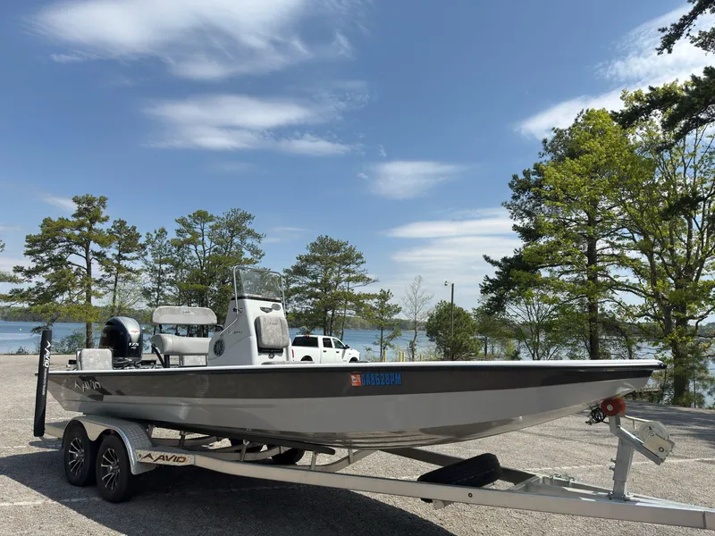 Slide: The Image of 2023 Avid 23 FS boat on trailer by lakeside, under clear blue sky. - 0