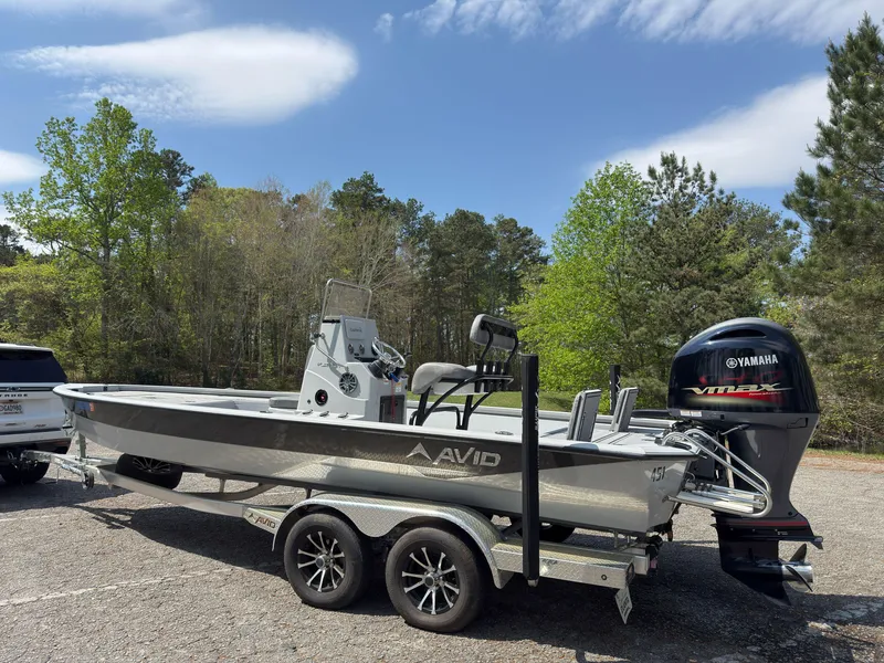 Slide: The Image of 2023 Avid 23 FS boat on trailer with Yamaha engine, parked outdoors. - 1