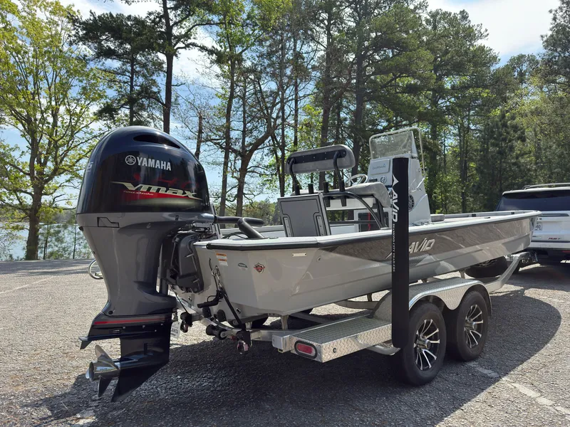 Slide: The Image of 2023 Avid 23 FS boat with Yamaha engine on a trailer, parked near a forested lake. - 2