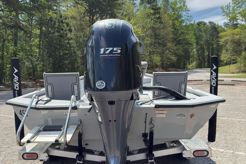 Slide: The Image of 2023 Avid 23 FS boat with 175 horsepower engine, parked in a wooded area. - 3