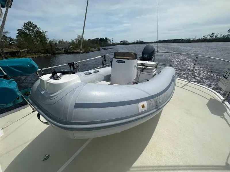Slide: The Image of 2019 Kadey-Krogen 44AE boat with inflatable dinghy on deck, docked by a scenic river. - 51