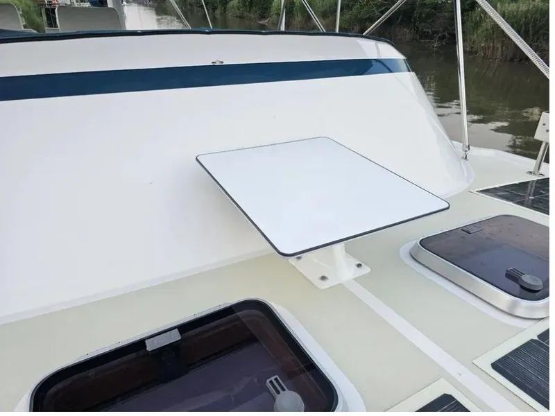Slide: The Image of 2019 Kadey-Krogen 44AE yacht deck with table and hatches, docked by a river. - 56