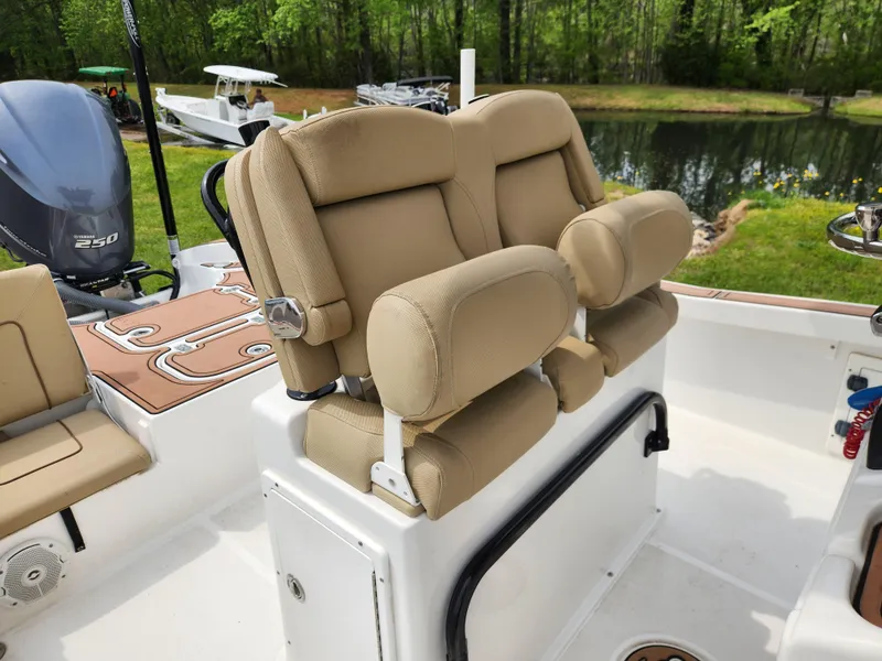 Slide: The Image of 2017 Sea Hunt BX 25 BR boat with tan cushioned seating, near a pond. - 11