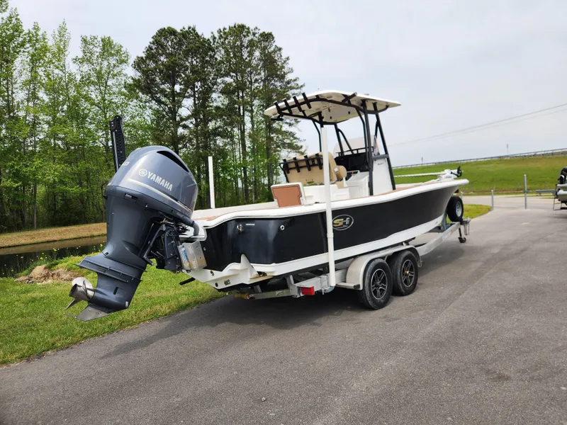 Slide: The Image of 2017 Sea Hunt BX 25 BR boat on trailer with Yamaha outboard, parked near trees. - 2