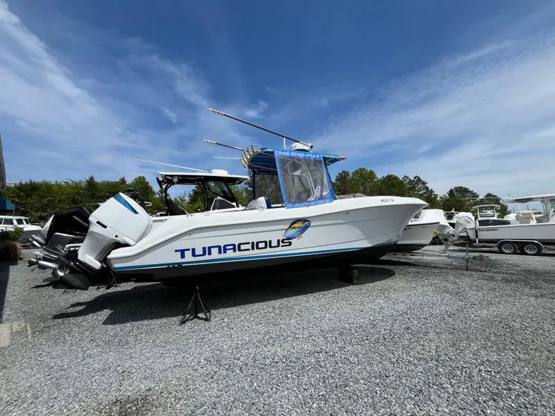 Slide: The Image of 2000 Hydra-Sports 2796 Vector boat named "Tunacious" on gravel, under a clear blue sky. - 2