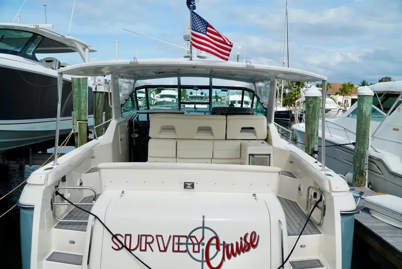 Slide: The Image of 1998 Tiara Yachts 4000 Express docked, featuring spacious deck and American flag. - 3