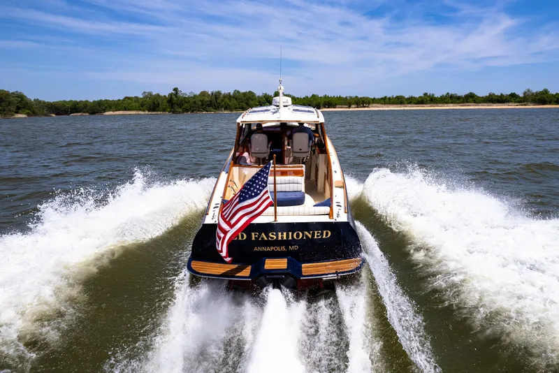 Slide: The Image of Hinckley Picnic Boat EP 2002 cruising on water with American flag, scenic background. - 14