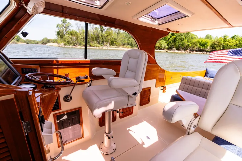 Slide: The Image of 2002 Hinckley Picnic Boat EP interior with white seating, wooden accents, and river view. - 22