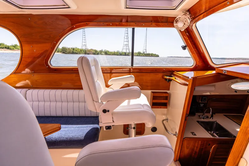 Slide: The Image of 2002 Hinckley Picnic Boat EP interior with plush seating and wood finish, overlooking serene waters. - 26