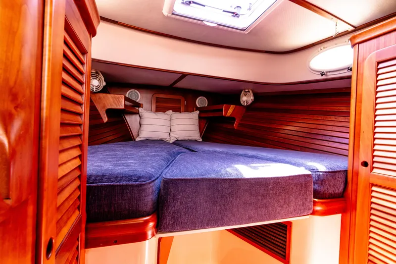 Slide: The Image of 2002 Hinckley Picnic Boat EP cabin with wooden interior and cozy bedding. - 33