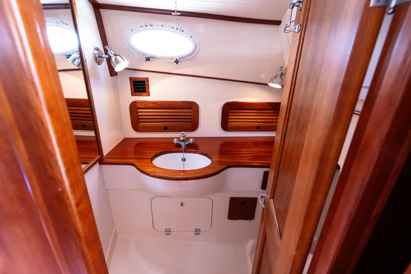 Slide: The Image of 2002 Hinckley Picnic Boat EP bathroom with wooden cabinetry and round porthole window. - 35