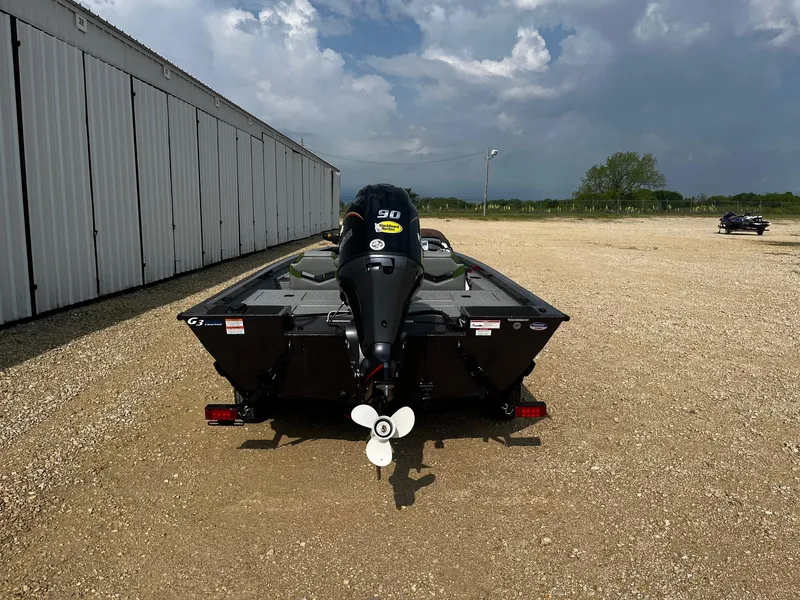 Slide: The Image of 2025 G3 Sportsman 1710 PFX boat, rear view, parked on gravel near a building. - 5