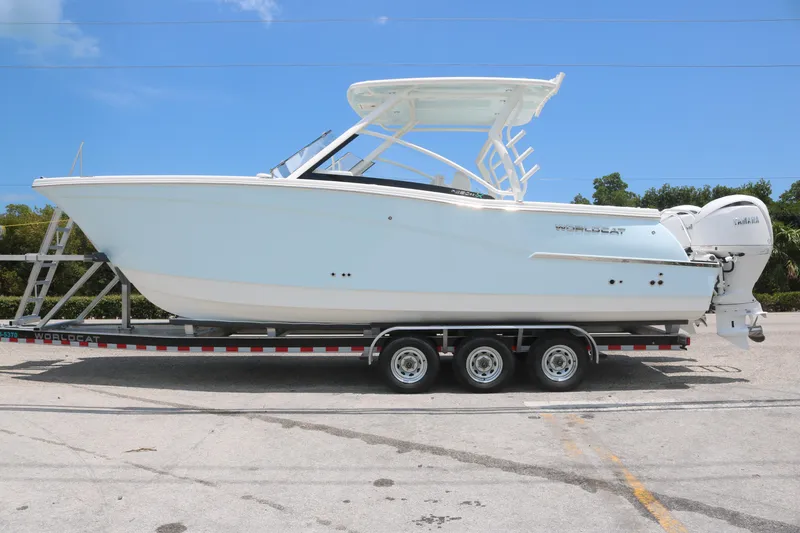 Slide: The Image of 2025 World Cat 280 DC boat on a trailer, side view under clear blue sky. - 1