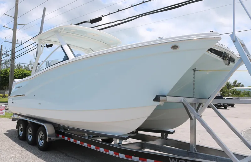 Slide: The Image of 2025 World Cat 280 DC boat on trailer, side view, under clear sky. - 2