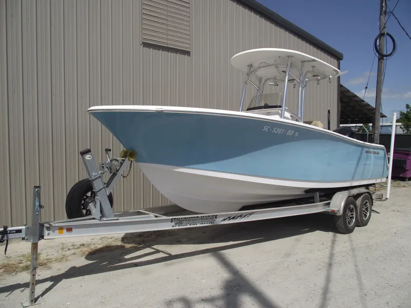 Slide: The Image of 2016 Sportsman Open 232 Center Console boat on trailer, parked beside a building. - 1