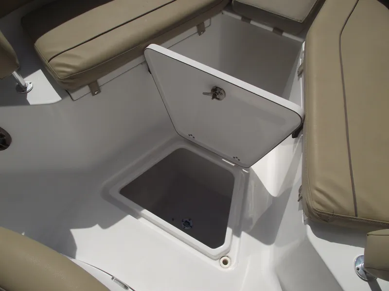 Slide: The Image of 2016 Sportsman Open 232 Center Console boat storage compartment with open hatch and cushioned seating. - 22
