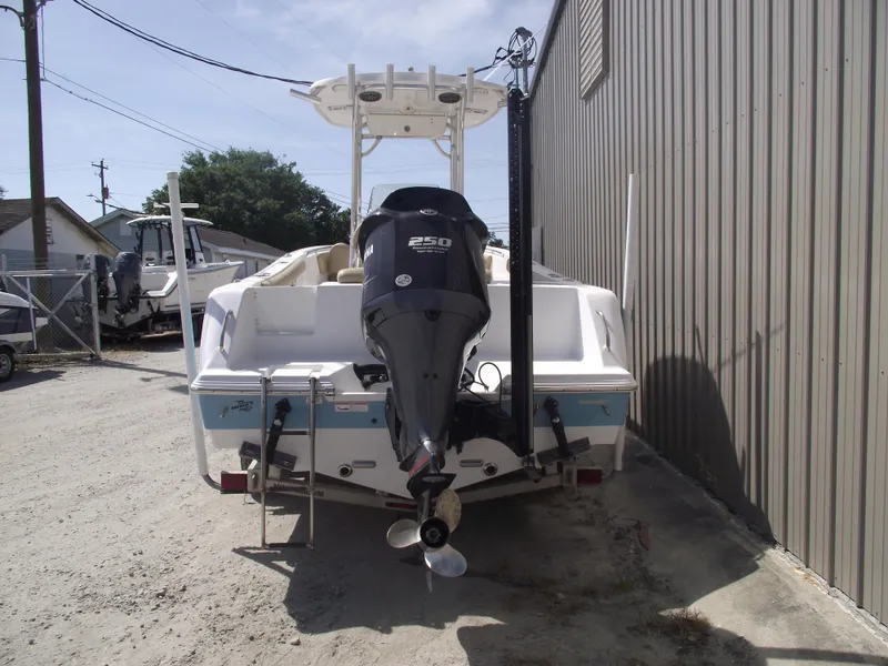 Slide: The Image of 2016 Sportsman Open 232 Center Console boat with outboard motor, parked near a building. - 3