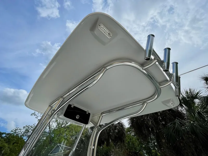 Slide: The Image of 2022 Front Runner 26 Center Console boat's T-top with rod holders against a blue sky. - 21