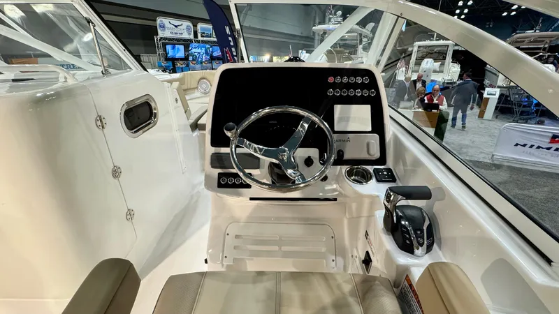 Slide: The Image of 2025 Edgewater 248 CX boat cockpit with modern steering and controls at a boat show. - 12