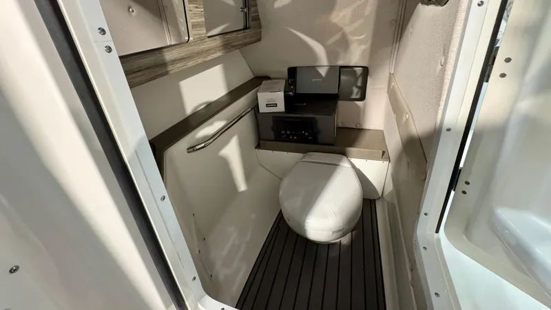 Slide: The Image of 2025 Edgewater 248 CX boat interior with compact marine toilet and storage. - 17