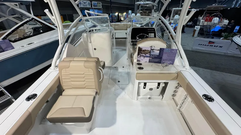 Slide: The Image of 2025 Edgewater 248 CX boat interior with beige seating and modern dashboard at a boat show. - 7