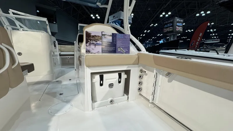 Slide: The Image of 2025 Edgewater 248 CX boat interior with seating, storage, and brochures on display. - 8