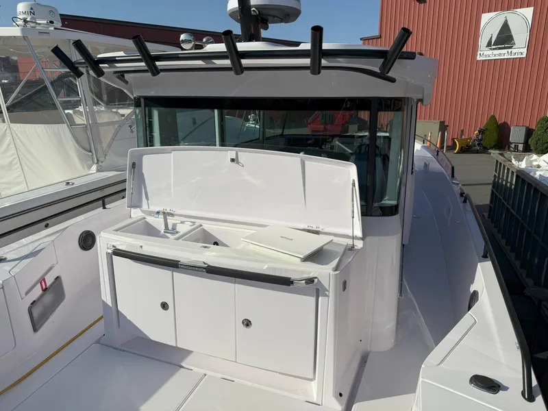 Slide: The Image of 2024 Axopar Cross Cabin boat with open storage compartment, docked at a marina. - 13