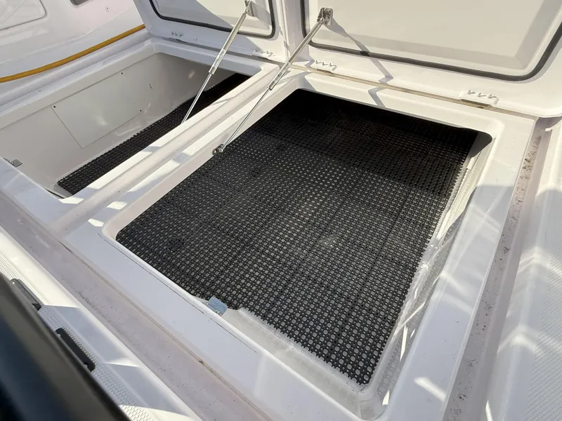Slide: The Image of 2024 Axopar Cross Cabin storage compartments with open hatches and black mats. - 25
