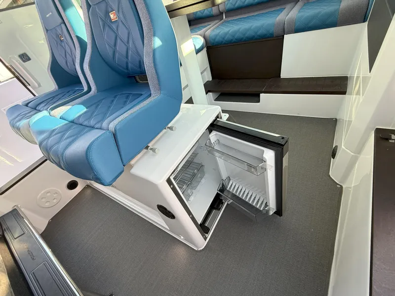 Slide: The Image of 2024 Axopar Cross Cabin interior with blue seating and open mini fridge. - 40