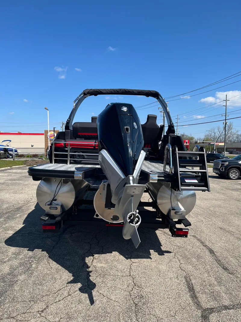 Slide: The Image of 2025 Bennington M Line boat, rear view with outboard motor, parked on pavement under clear blue sky. - 3