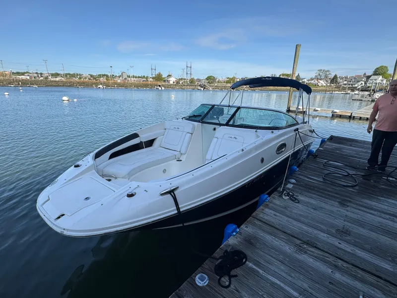 The Image of 2014 Sea Ray 260 Sundeck boat docked on calm water, clear sky background. - 0