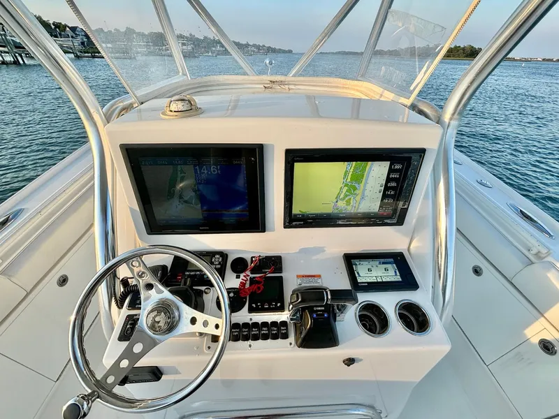 Slide: The Image of 2013 Buddy Davis 34 Center Console helm with dual displays and steering wheel on open water. - 19