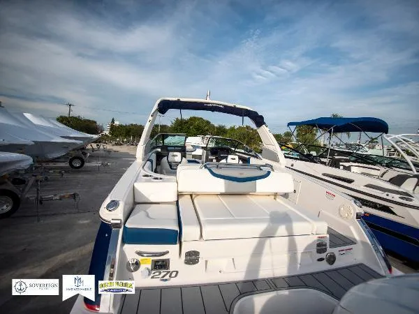 Slide: The Image of 2024 Chaparral 270 OSX boat, rear view, docked under a clear blue sky. - 15