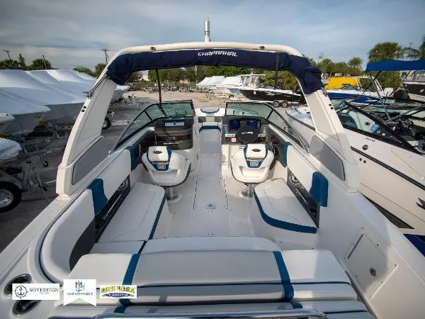 Slide: The Image of 2024 Chaparral 270 OSX boat interior with seating and dashboard, docked outdoors. - 16