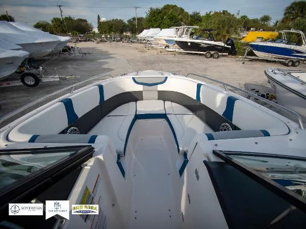 Slide: The Image of 2024 Chaparral 270 OSX boat interior with spacious seating, parked among other boats. - 25